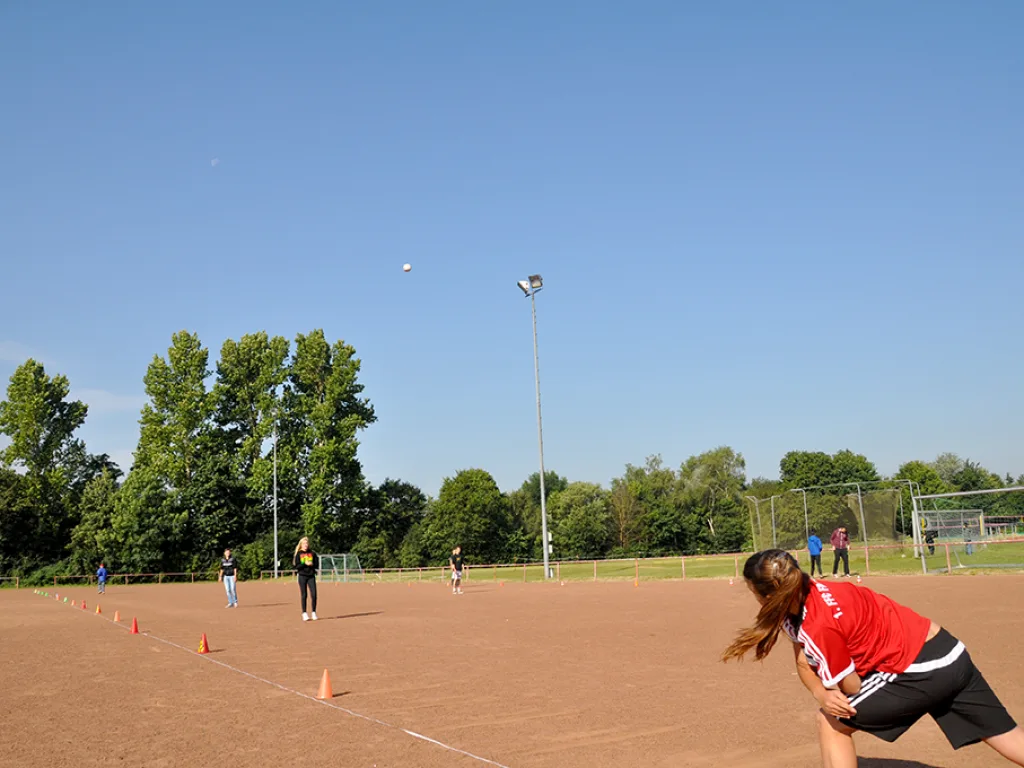 Jugendliche beim Ballwurf auf dem Sportplatz.